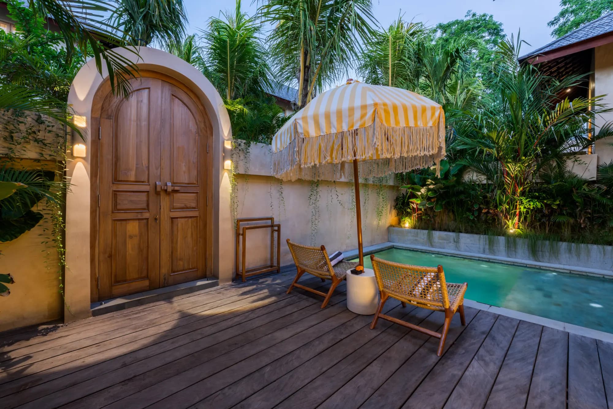 Nighttime facade with glowing archway doors overlooking courtyard pool