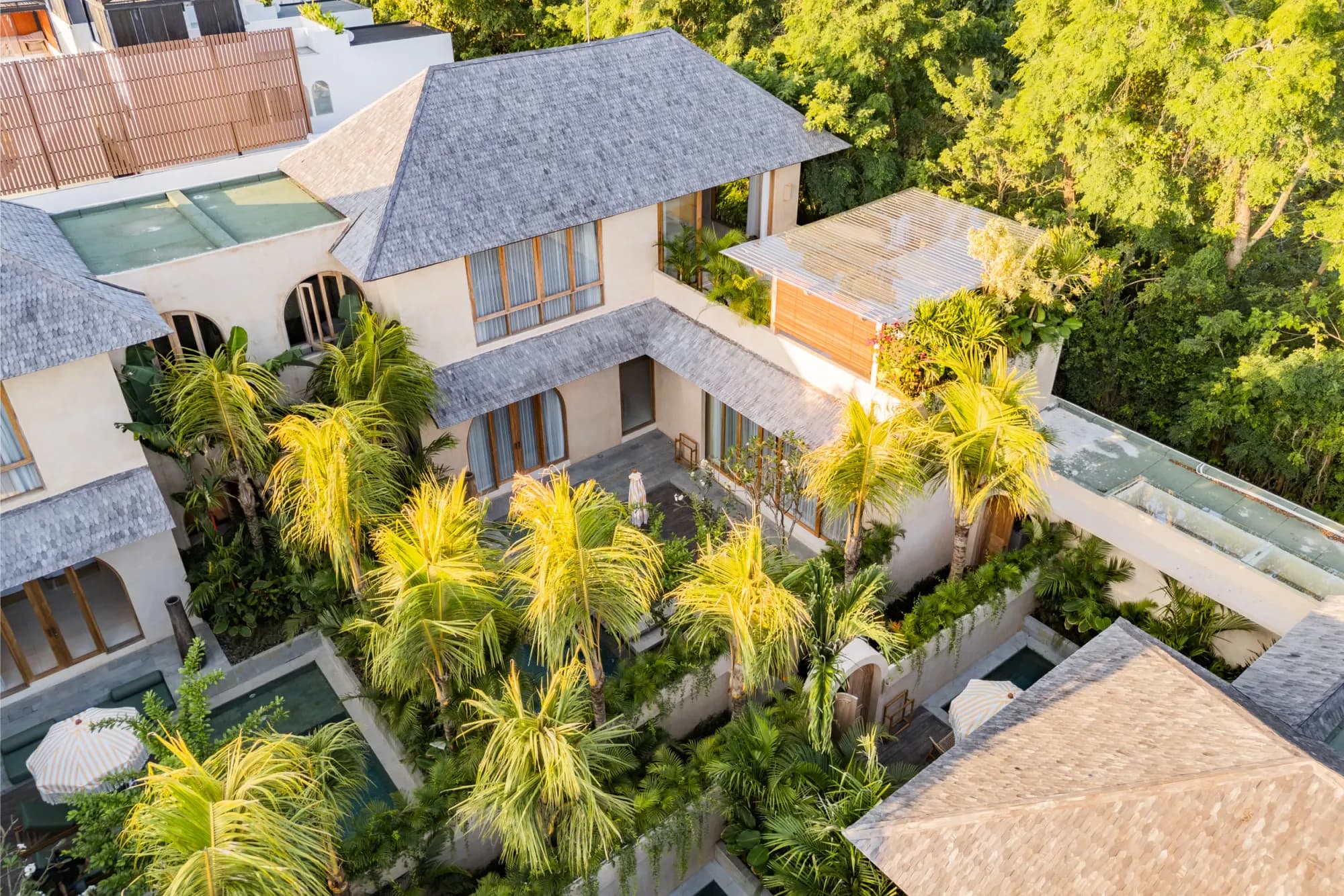 Aerial view of villa compound with teal pools and palms