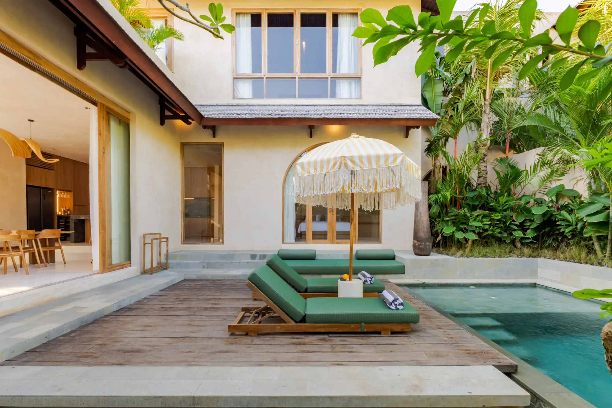 Villa interior opening to pool area with green loungers