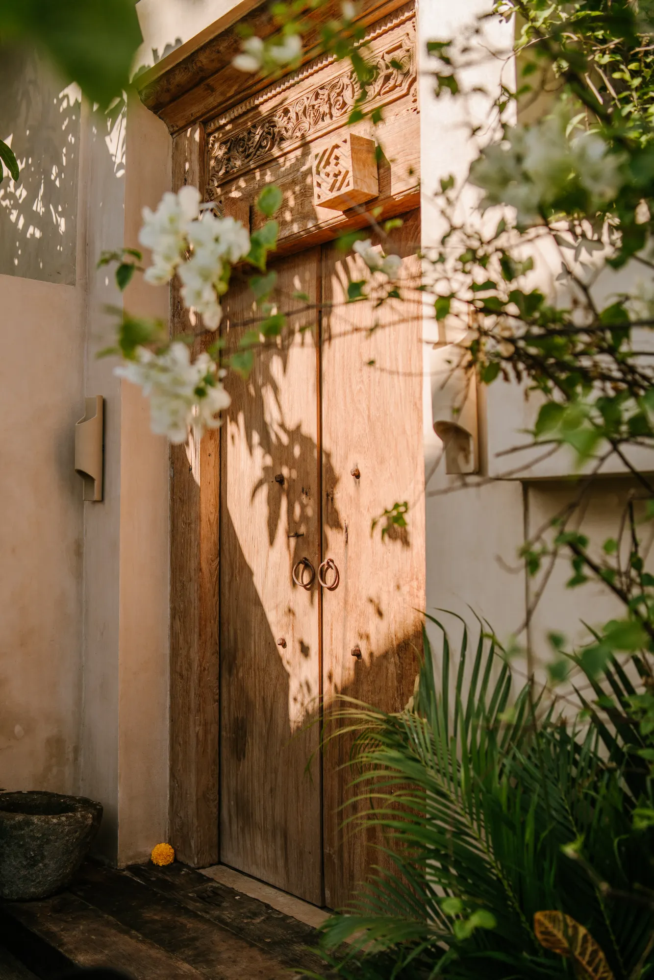 Carved wooden door detail with flowering plants and shadows