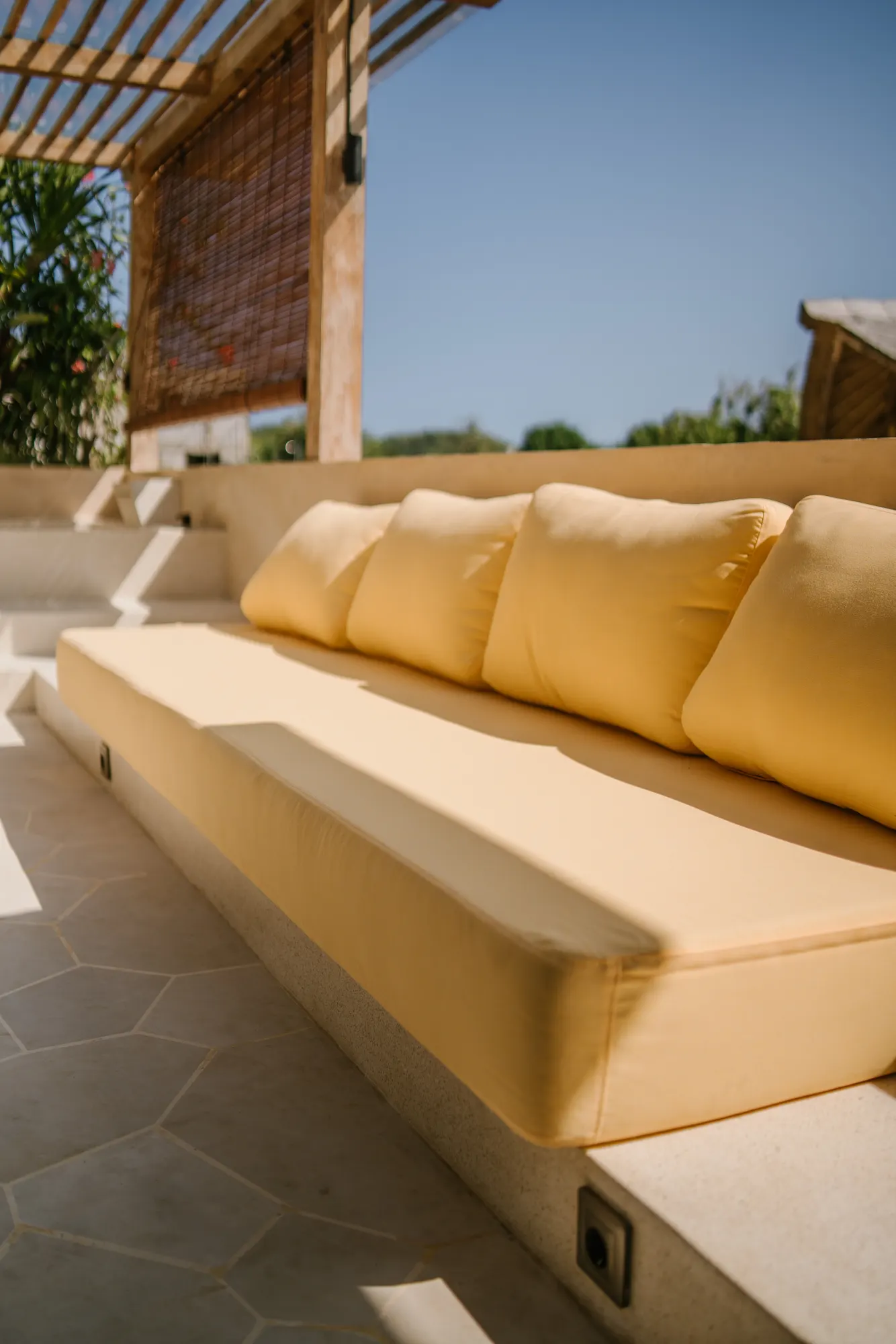 Outdoor seating area with yellow cushions and pergola