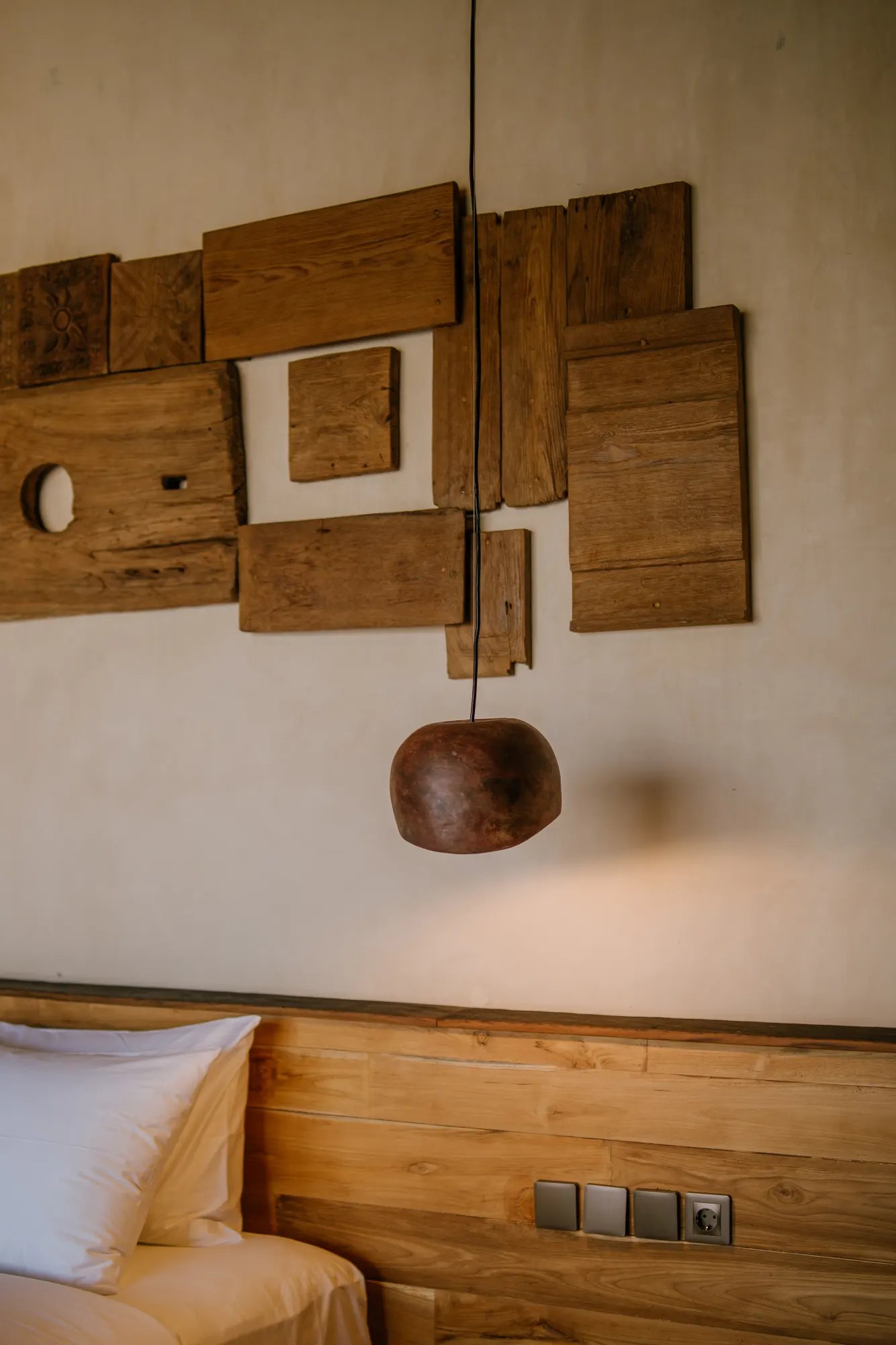 Bedroom wall art installation with wooden elements and hanging pendant