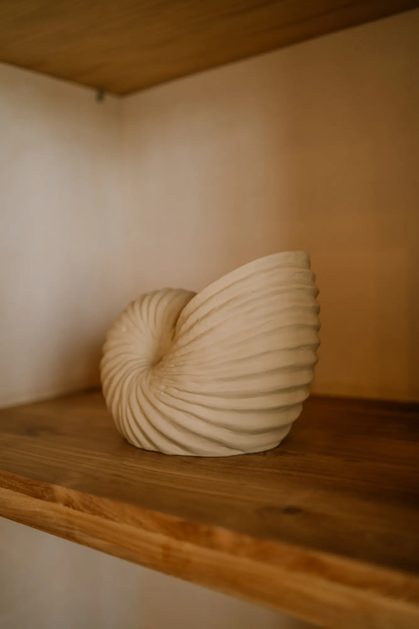 Terracotta sculptural form displayed in minimalist interior space