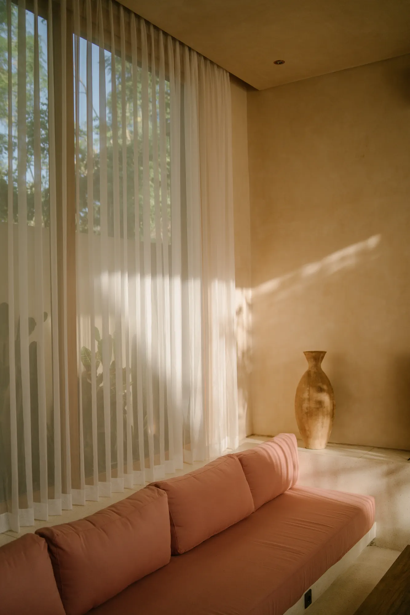 Interior sitting area with coral cushions and botanical window view