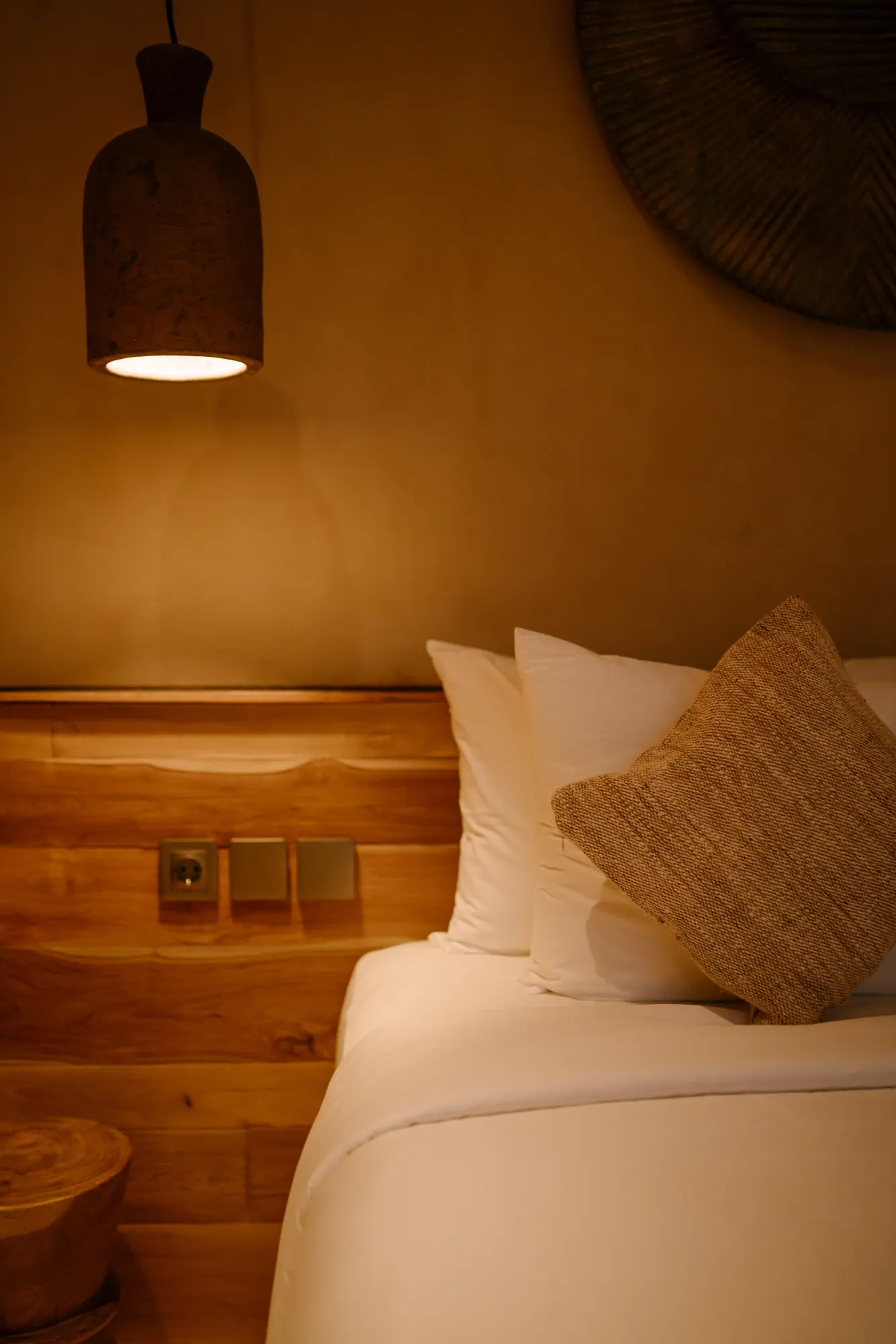 Tall dark pendant light above bedroom bed