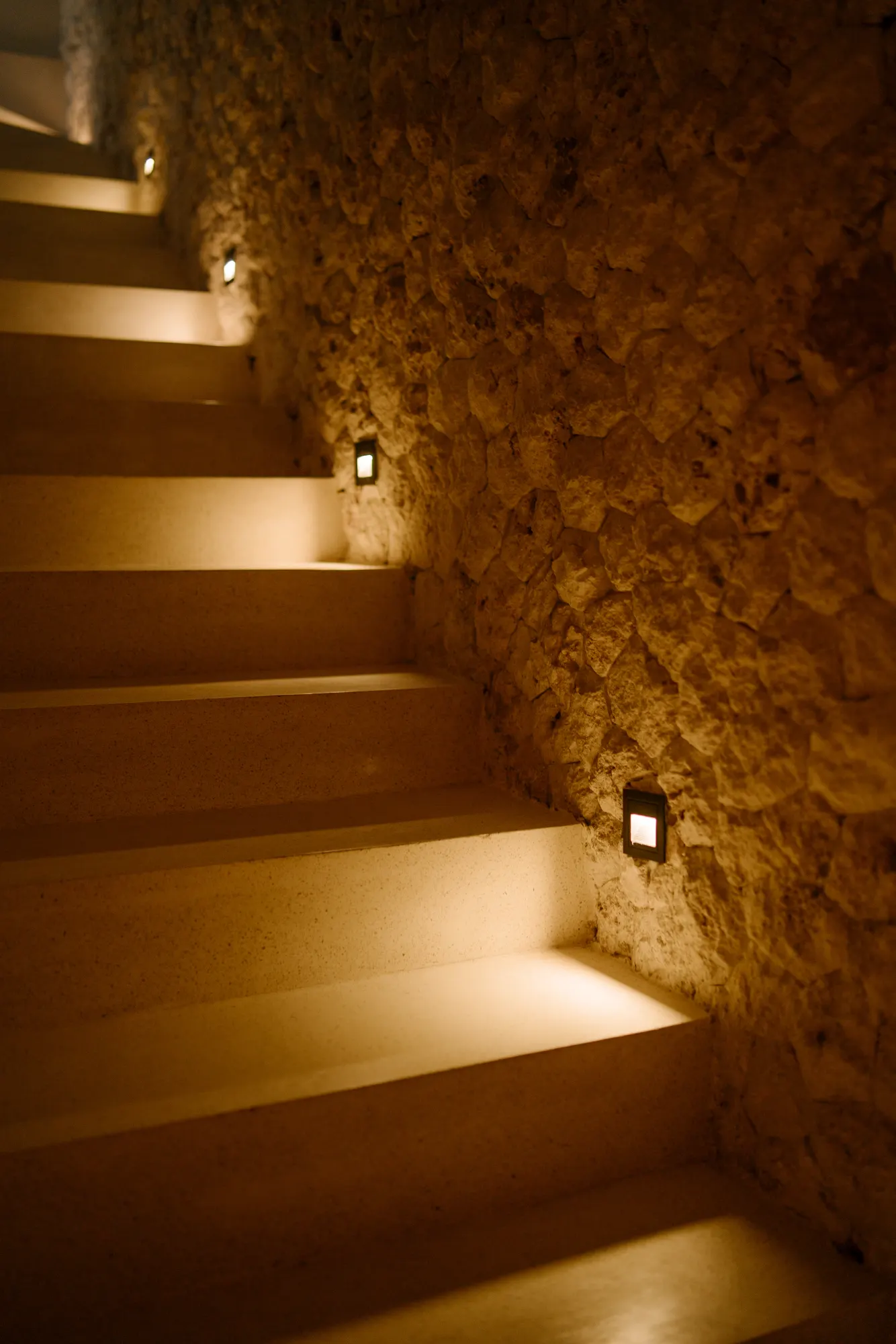 Illuminated staircase with stone wall at night
