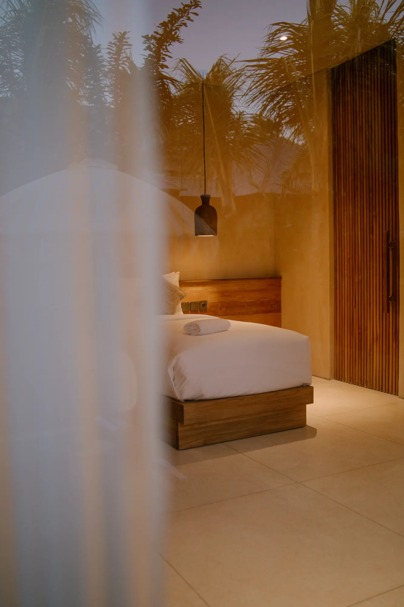 Minimalist bedroom with palm fronds and pendant light