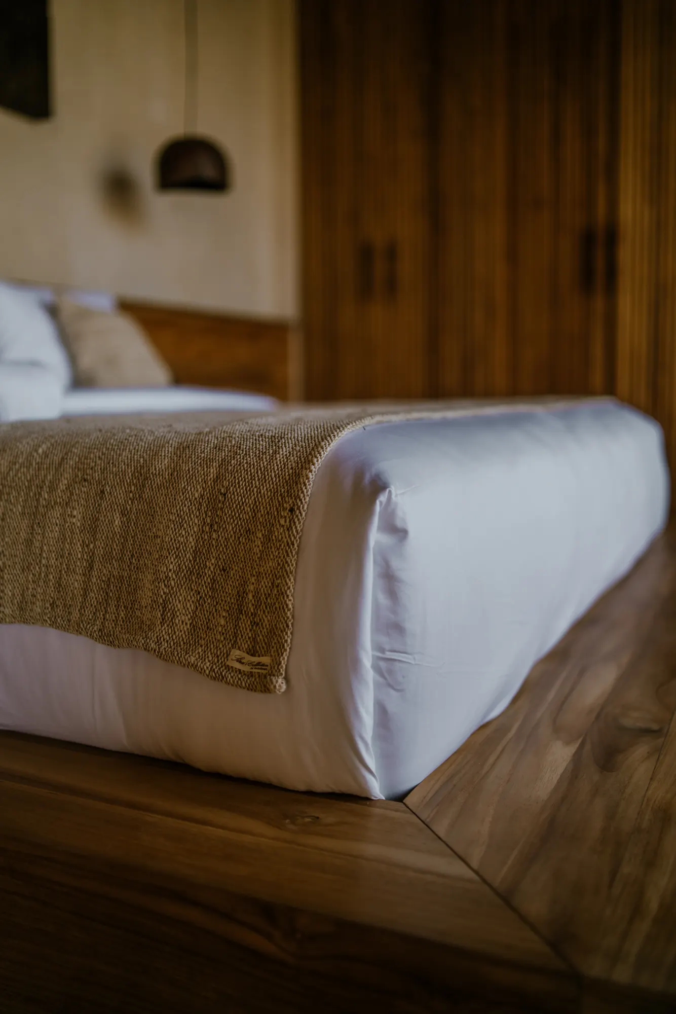 Bedroom with neutral bedding and woven texture throw