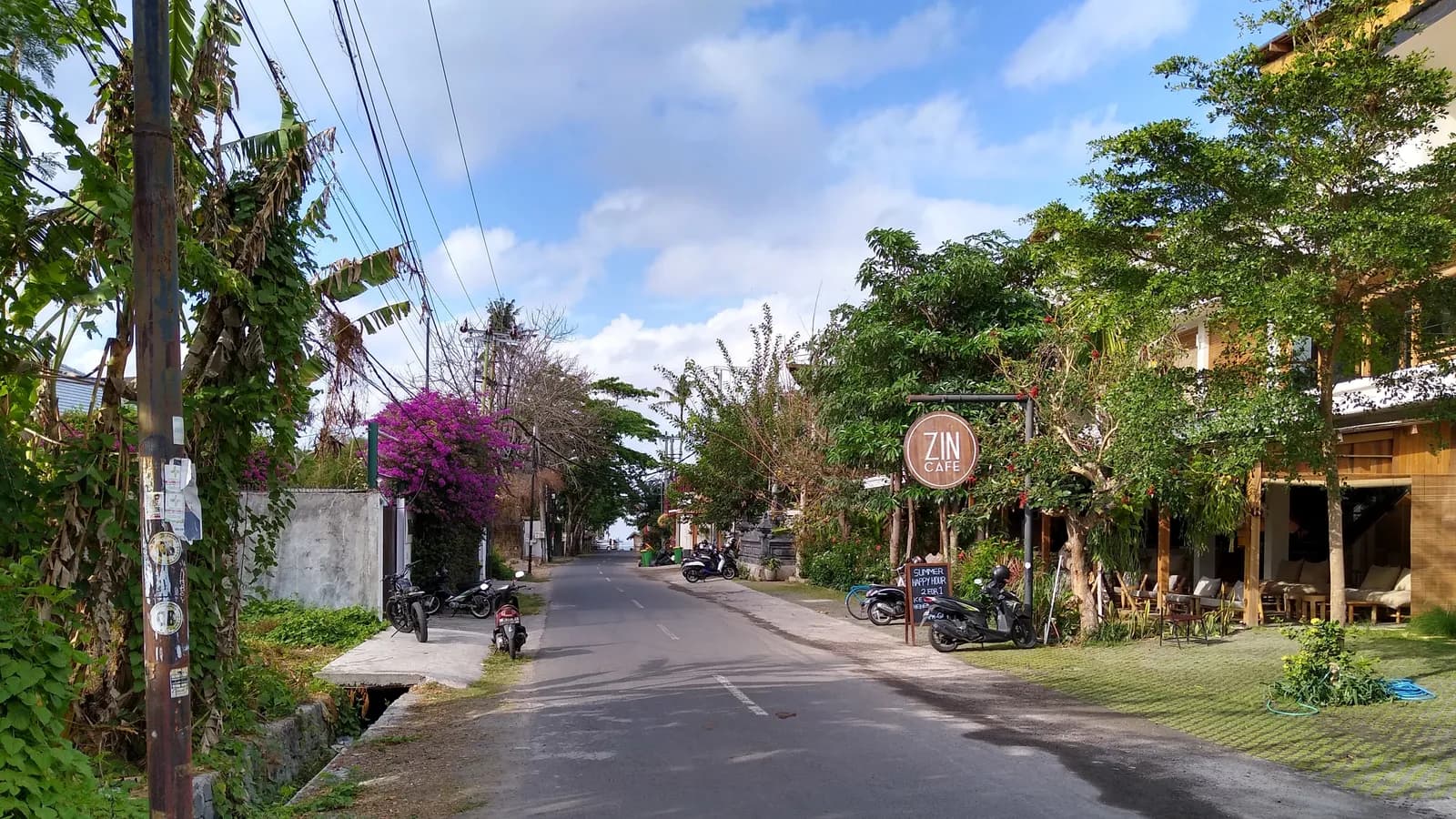 A quiet Bali street lined with cafes, scooters and greenery